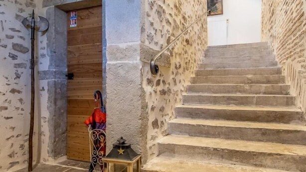A stone staircase leading to a wooden door, with a coat rack and a lantern on the landing.