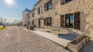A rustic building with a gravel patio, wooden deck, and outdoor seating area.
