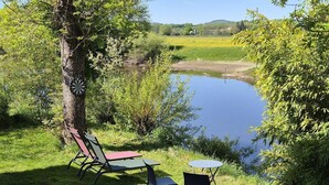 A tranquil outdoor seating area with a table and chairs, a dartboard, and a view of a lake.