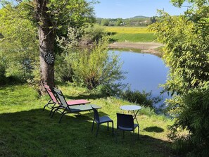A tranquil outdoor seating area with a table and chairs, a dartboard, and a view of a lake.