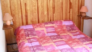 A bed with a pink and purple quilt, wooden headboard, and two bedside lamps.