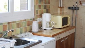 A kitchen with a sink, a coffee maker, a microwave, and a cabinet.
