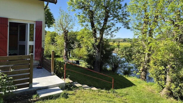 A house with a red door, a wooden staircase, and a view of a river.