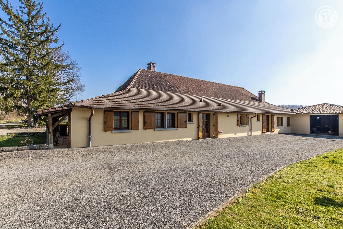 Una casa a due piani con vialetto sterrato e veranda coperta.