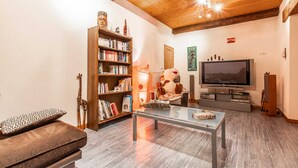 Una sala de estar acogedora con techo de madera, una estantería, un televisor y un sofá cómodo.
