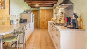 Una cocina con vigas de madera, una isla central y un comedor con sillas.