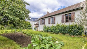A house with a garden, a visible fence, and a clear sky. - Au Fil de la Cozanne (PARIS L'HOPITAL)