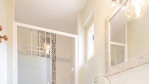 A modern bathroom with a glass shower enclosure, a wooden vanity with a sink, and a mirror above the vanity. - Au Fil de la Cozanne (PARIS L'HOPITAL)