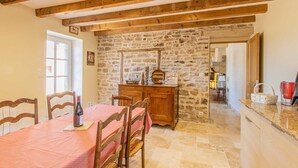 Un comedor rústico con pared de piedra, vigas de madera y una mesa dispuesta para dos.