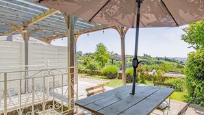 An outdoor patio with a table and chairs, a pergola with a canopy, and a view of the countryside. - Maison du Mont Rome - Saint Sernin DU Plain (SAINT SERNIN DU PLAIN)