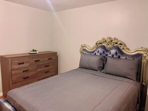 Cozy retreat with a single bed featuring a tufted headboard and a dresser with multiple drawers.