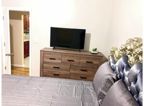 Cozy retreat with a large bed, dresser, and flat-screen TV.