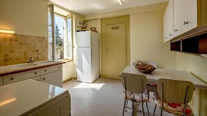 A compact kitchen with a refrigerator, a sink, and a dining area with chairs and a table. - Le Chevalier - Saint-sernin-du-plain (SAINT-SERNIN-DU-PLAIN)