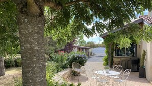 A patio with outdoor furniture, a stone pathway, and a view of a building in the background. - le Petit Midi - Cluny (CLUNY)