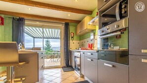 A modern kitchen with stainless steel appliances, a dining area with a view, and a sliding glass door leading to an outdoor patio. - le Petit Midi - Cluny (CLUNY)