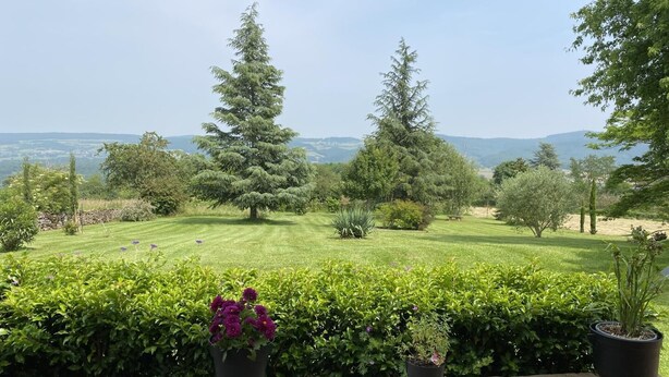 A stone wall with potted plants and a view of a well-maintained lawn and trees. - le Petit Midi - Cluny (CLUNY)