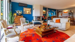 A modern living room with a blue accent wall, a fireplace, and a dining area with wooden furniture. - le Petit Midi - Cluny (CLUNY)