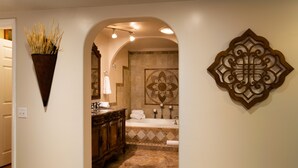 A bathroom with a bathtub, a sink, and a vanity. There is a decorative wall piece and a plant on the wall. - Charming 2 bedroom 2 bathroom home with jetted tub! (Plains)