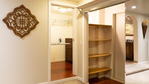 A hallway with a wooden floor, a decorative wall piece, and a closet with open doors. - Charming 2 bedroom 2 bathroom home with jetted tub! (Plains)