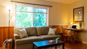 A living room with a sofa, a coffee table, a lamp, a chair, and a desk with a laptop. - Charming 2 bedroom 2 bathroom home with jetted tub! (Plains)