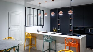 A modern kitchen with a white countertop, black cabinets, and colorful bar stools.