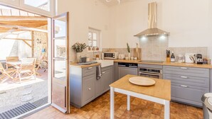 A modern kitchen with grey cabinets, a wooden dining table, and a large window.
