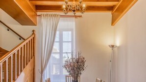A wooden dining room with a chandelier, a table, chairs, and a vase of flowers.