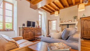 A cozy living room with a wooden ceiling, a fireplace, a television, and a comfortable seating area.