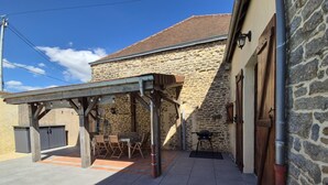 A stone building with a covered patio, outdoor seating, and a pool.