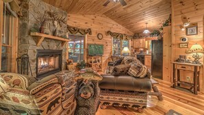 Un intérieur chaleureux de chalet en bois avec une cheminée, un canapé en cuir et une décoration rustique.