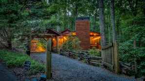 Une cabane avec une façade en bois, une allée en gravier et une clôture en bois.