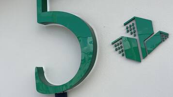 Un grand panneau vert avec le chiffre « 5 » et un petit symbole représentant un bâtiment sur la droite.