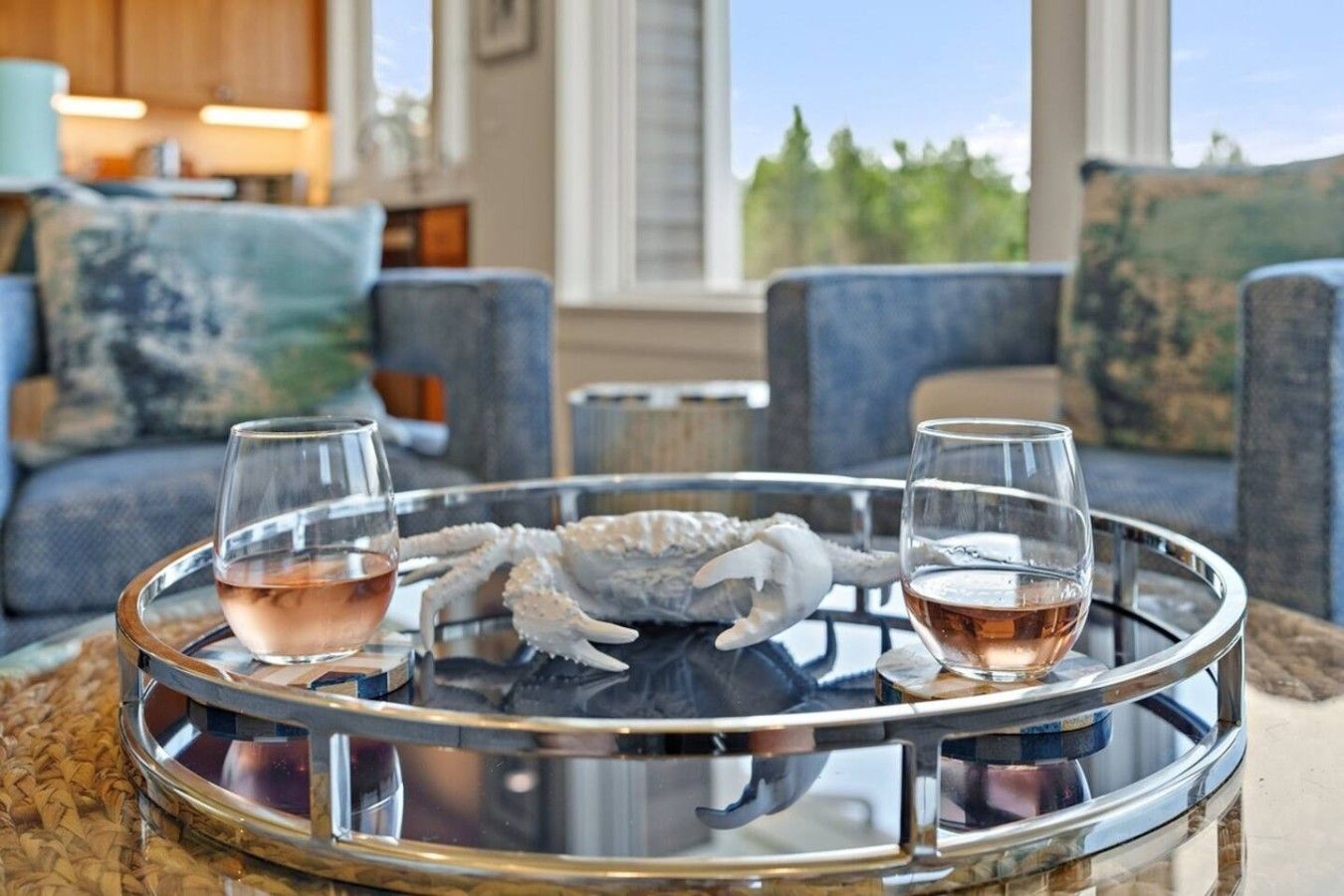 Ein Glastablett mit zwei Gläsern Roséwein und einer dekorativen Krabbenschalen-Mitteldeko auf einem Tisch.