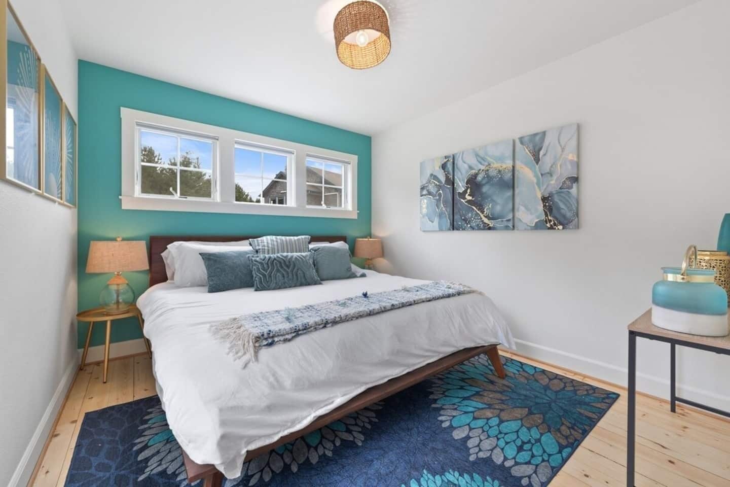 A bedroom with a large bed, two bedside tables, a window, and a wall-mounted artwork.