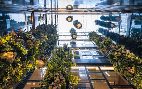 A modern interior with glass railings and greenery.
