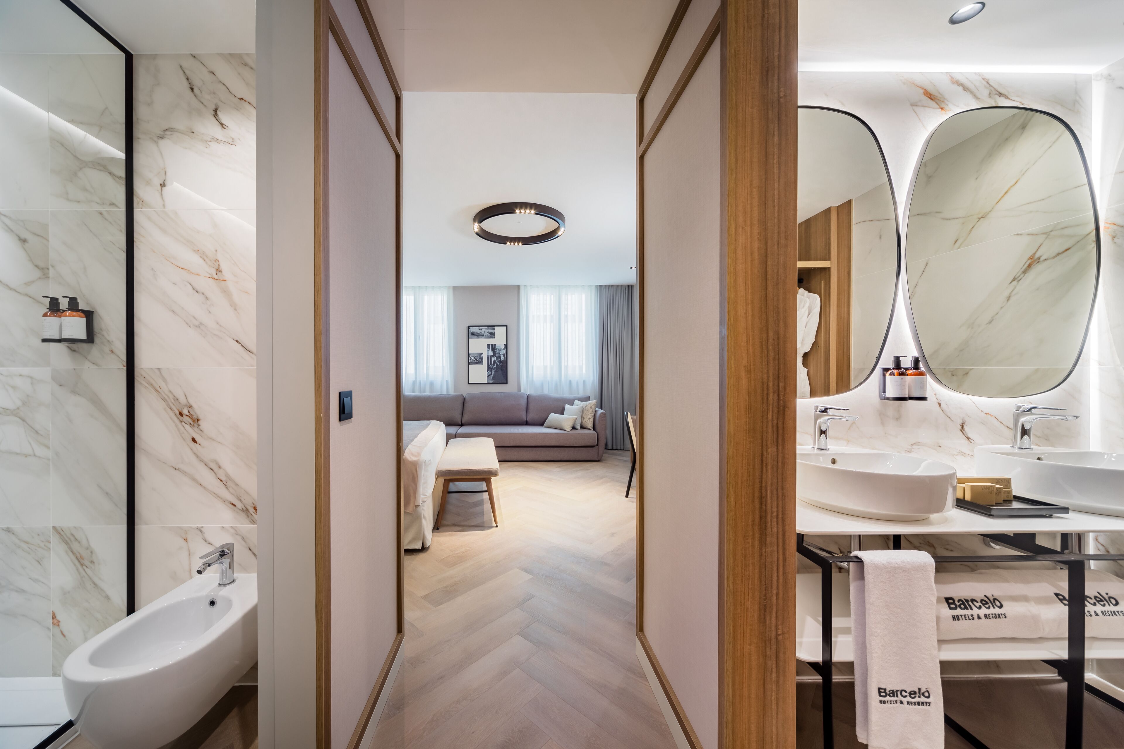 Un baño moderno con un bidé, un espejo grande y un perchero con una toalla de la marca.