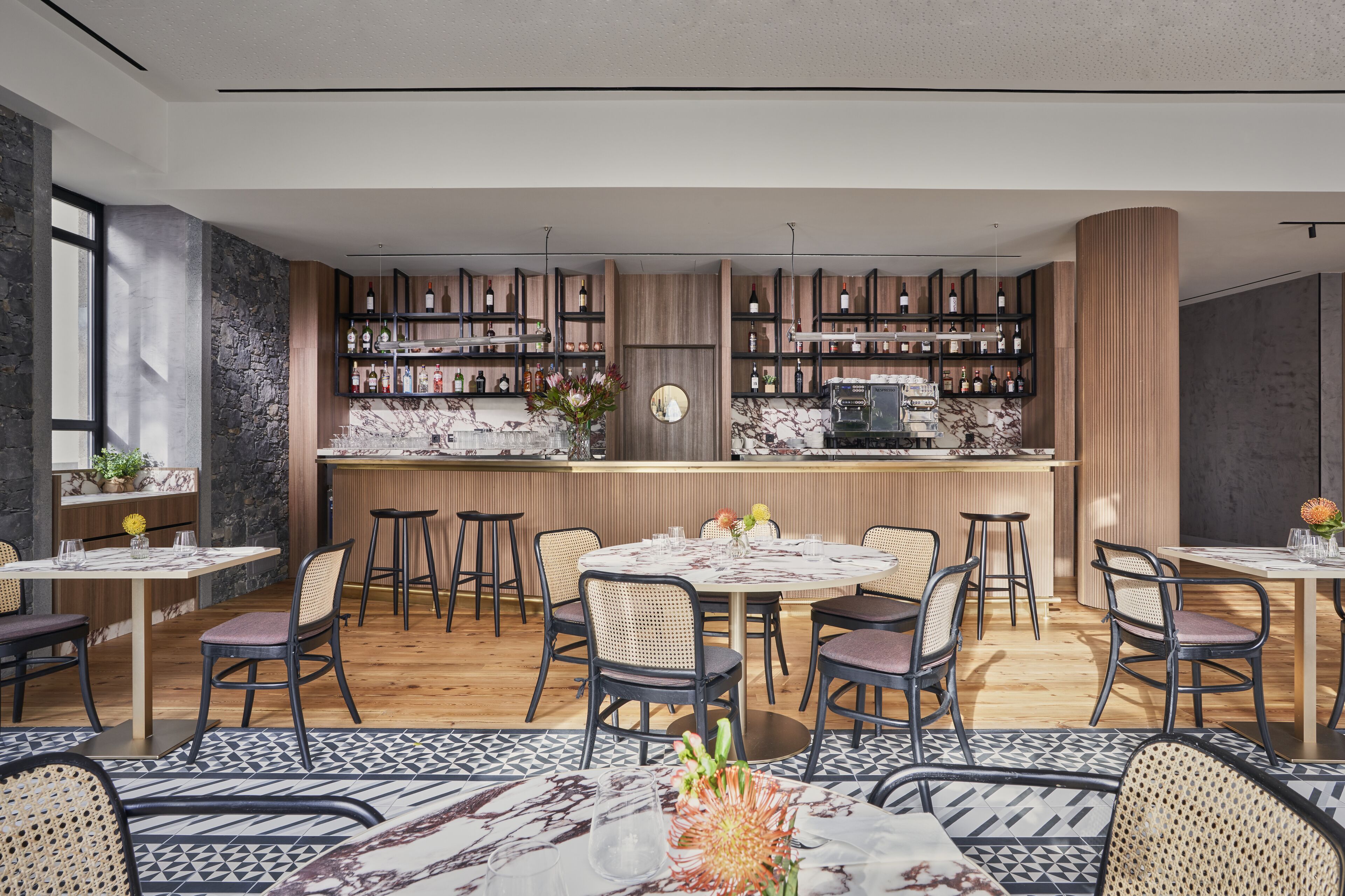Un ristorante moderno con zona bar, elementi in legno e pavimento in marmo.