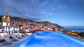A rooftop pool with lounge chairs, a bell tower, and a view of a coastal town. - Barcelo Funchal Oldtown (Funchal)