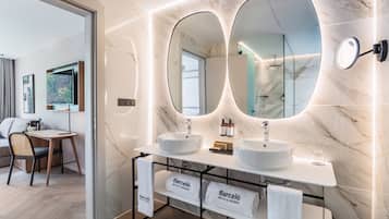 A modern bathroom with two sinks, large mirrors, and a vanity with towels.
