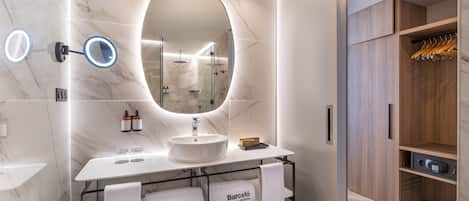 Un baño moderno con un espejo ovalado grande, un lavabo blanco y un armario de madera.