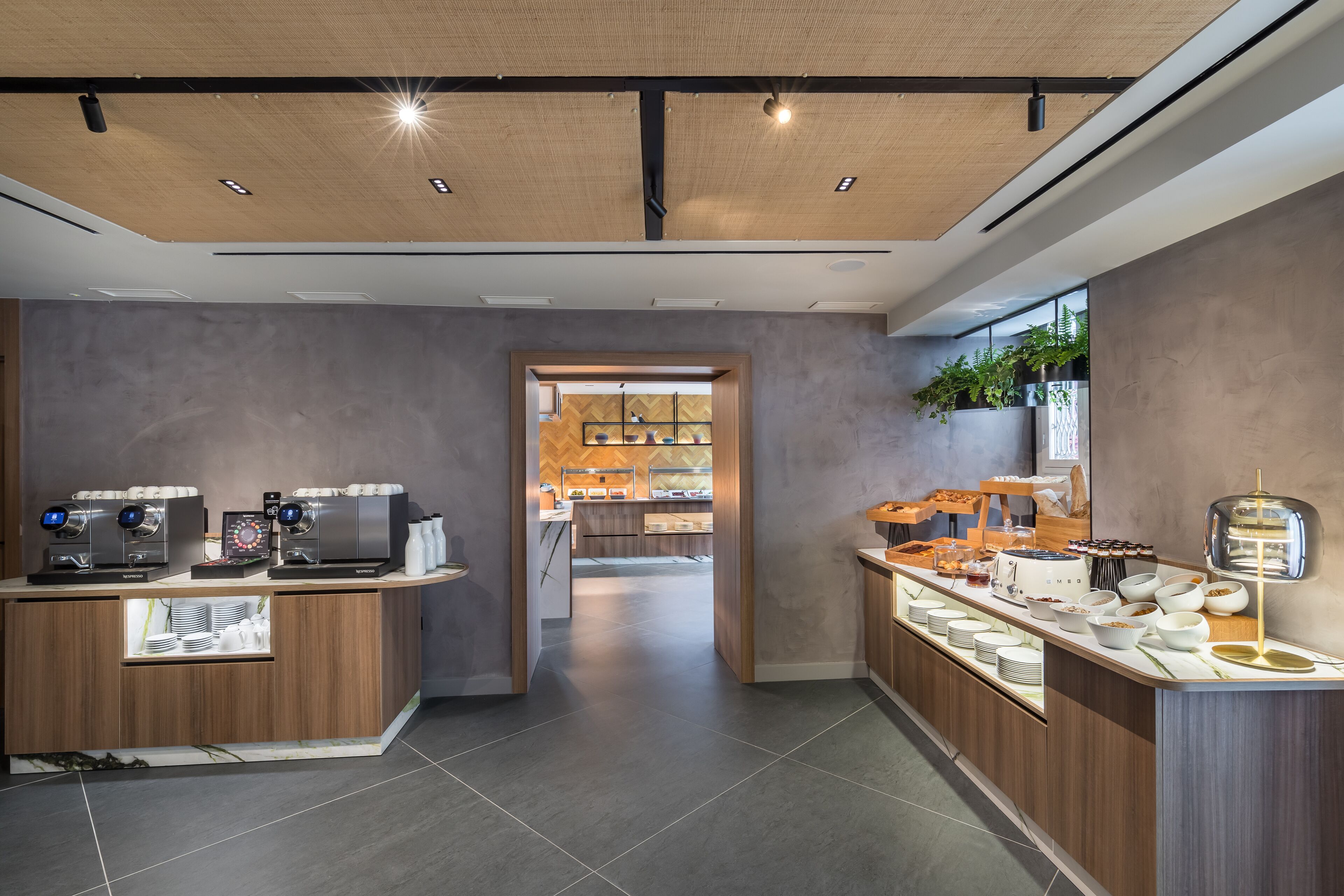 A modern cafe with a wooden counter, coffee machines, and a variety of food items.