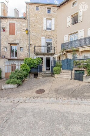 A courtyard with stone buildings, a small garden, and a gate.
