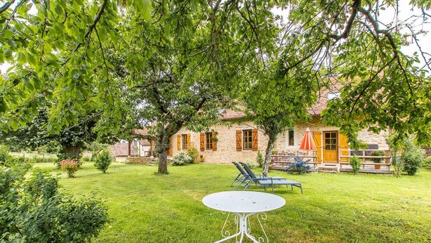 Ein Steinhäuschen mit Garten, einem runden Tisch und zwei Stühlen.