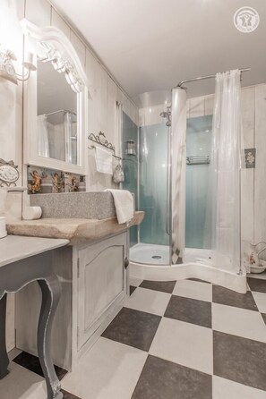 Bathroom features a vanity with a large mirror and a shower with a glass door.