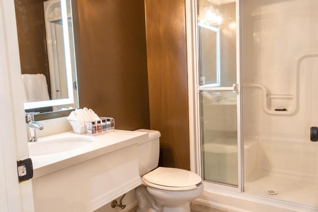 A bathroom with a white sink, toilet, and a glass-enclosed shower.