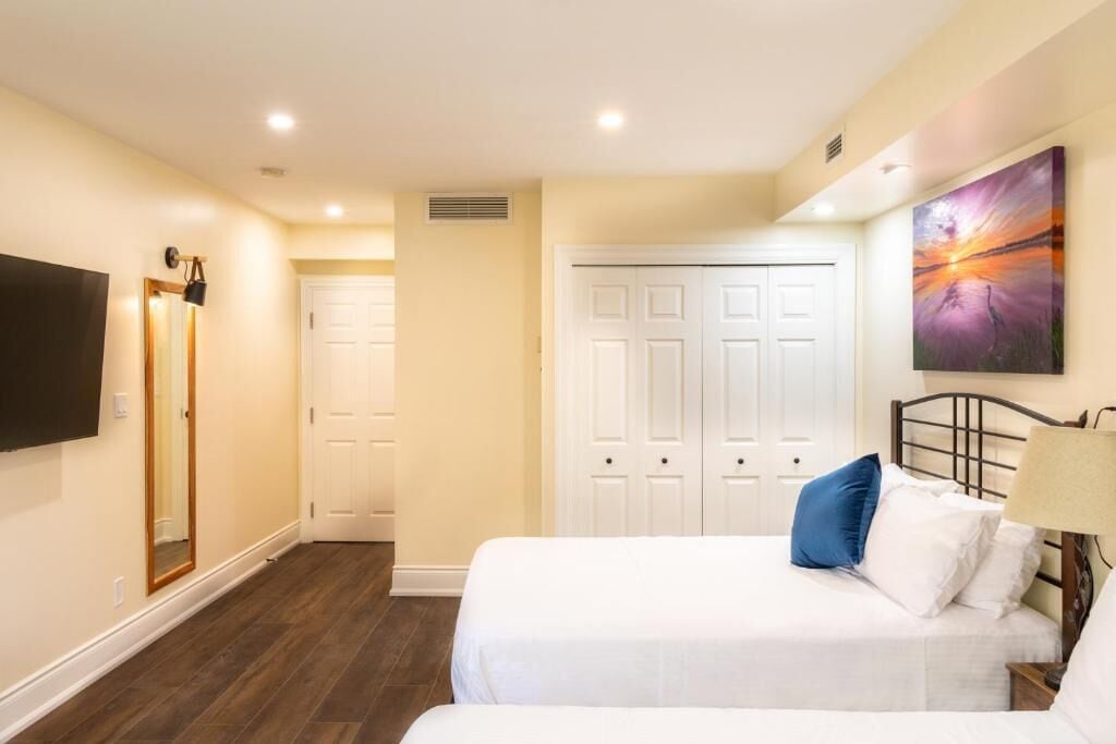 A bedroom with two beds, a TV, and a painting on the wall.