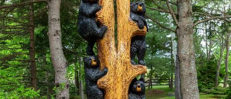 A wooden sculpture of bears climbing a tree with a sign reading "Fairy Bay Lakehouse".