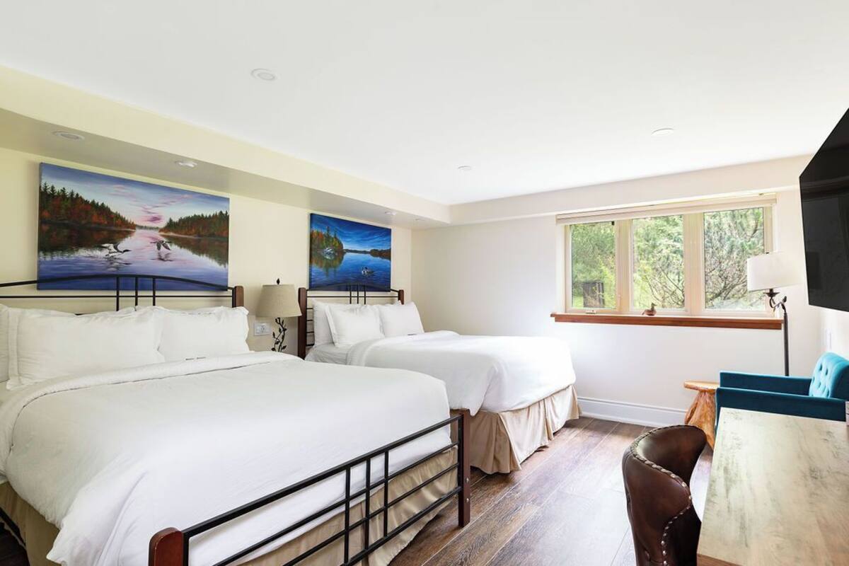 Habitación de hotel con dos camas, un escritorio y una ventana.