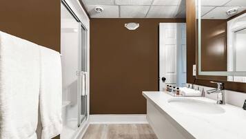 Une salle de bain moderne avec un grand miroir, un lavabo blanc et une cabine de douche en verre.