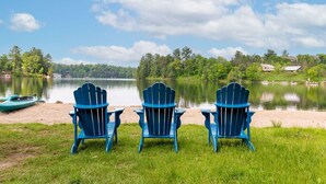 Three blue Adirondack chairs facing a lake with boats and houses in the background. - Fairy Bay Lakehouse (Huntsville)